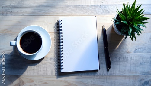 Sunlit desk flat lay with blank notebook, coffee and plant