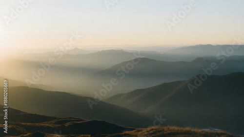 Beautiful morning view of a misty sunrise over the mountain valley as golden clouds and fog settle across the forest hills during a peaceful dawn landscape