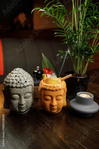 Colorful drinks served in decorative Buddha and monk cups at a cozy restaurant