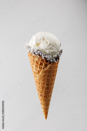 Enjoy creamy vanilla ice cream cone with chocolate and coconut toppings during a warm summer day