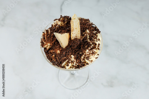 Delicious dessert showcases creamy layers, crunchy toppings, and rich chocolate in a stylish glass bowl at a casual dining spot