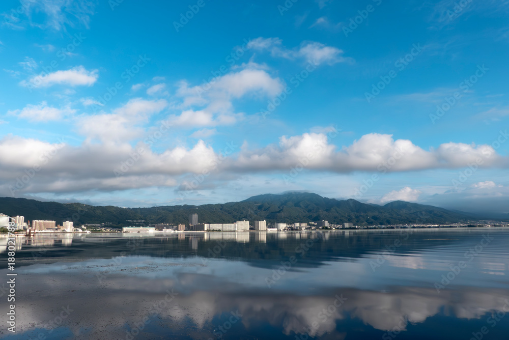 Obraz premium 早朝の静かな琵琶湖 大津市のマンション群と雲が湖面に映る風景