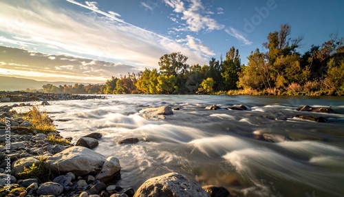 Golden Hour Sunlight Reflecting on a Rushing River with Autumn Trees.