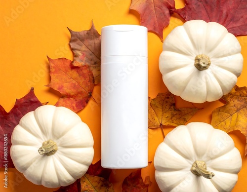 White bottle mockup is surrounded by autumn leaves and mini white pumpkins on orange background
