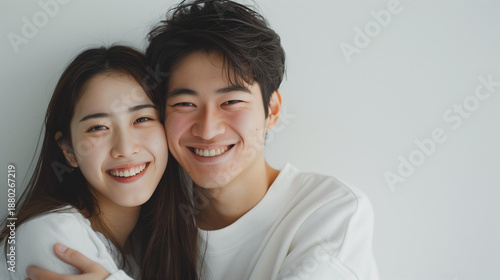 Happy young Japanese couple embracing and laughing together at home with warm intimate atmosphere