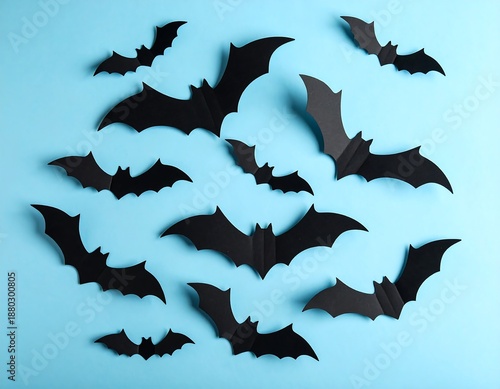 Black paper bat cutouts arranged on a light blue background