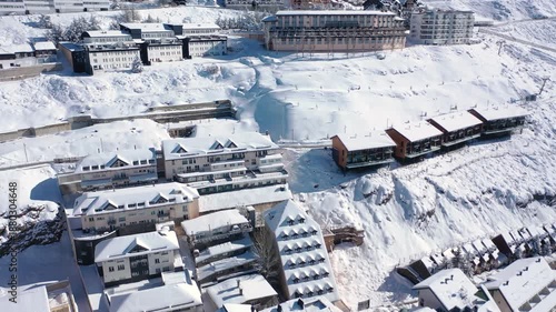 Aerial 4K video from a drone to Sierra Nevada ski resort on a sunny winter day in the mountains, Spain. Sierra Nevada is the largest mountain range near the city of Granada in Spain with snow. Sierra 
