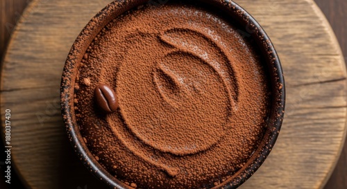 Rich chocolate dessert dusted with cocoa powder rests on a wooden surface.