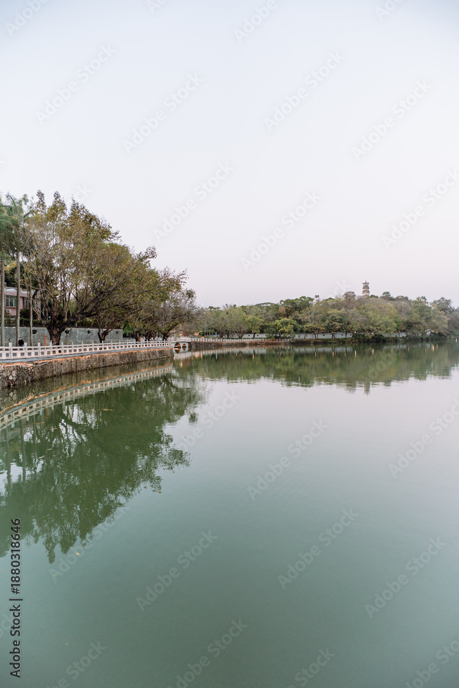 Obraz premium Tranquil Lake Reflection with Trees and Walkway - Huizhou West Lake
