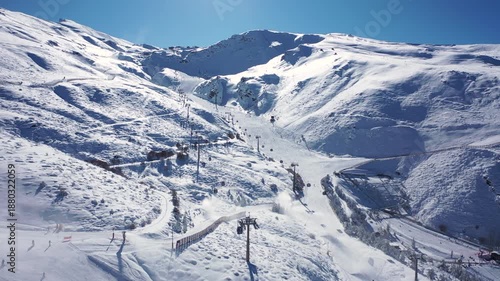 Aerial 4K video from a drone to Sierra Nevada ski resort on a sunny winter day in the mountains, Spain. Sierra Nevada is the largest mountain range near the city of Granada in Spain with snow. Sierra 