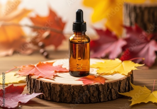 Amber glass dropper bottle with essential oil or serum on a rustic wood slice adorned with colorful autumn maple leaves, soft focus background