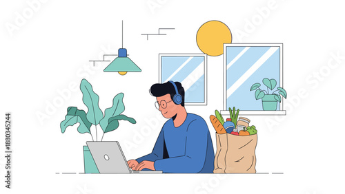 Man wearing headphones working on his laptop at a kitchen table with a paper bag full of fresh healthy groceries.