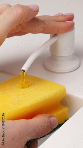 Wallpaper Mural Female hand press on built-in dispenser in the sink with detergent. Woman washing dishes by yellow sponge with soap in white kitchen. Housekeeping concept. Vertical footage Torontodigital.ca