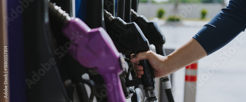 A close-up image of a gas station attendant's hand holding a fuel dispenser.	

