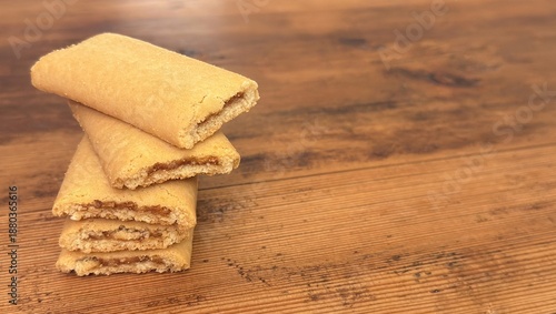 Homemade fig newtons cookies on rustic wooden table – soft layered fig bars with golden crust and copy space