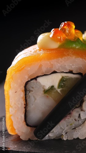 Wallpaper Mural Take one sushi roll from black slate platter using chopsticks, Closeup. Vertical footage Torontodigital.ca