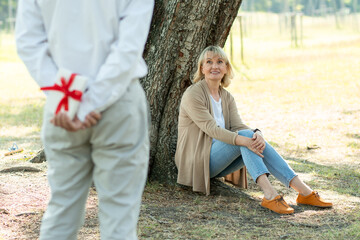 husband take gift to surprised wife in park, old love couple in valentine day concept
