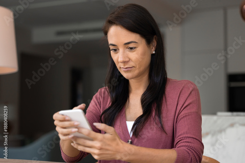 Slika na platnu Attractive Latina woman using modern smart phone at home, checking messages, tex