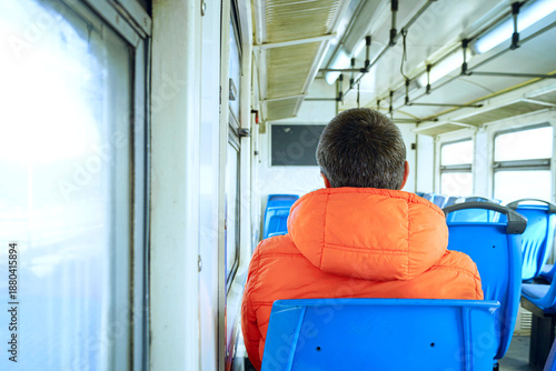 Foto Back view of solitary passenger facing train window inside quiet suburban carriage