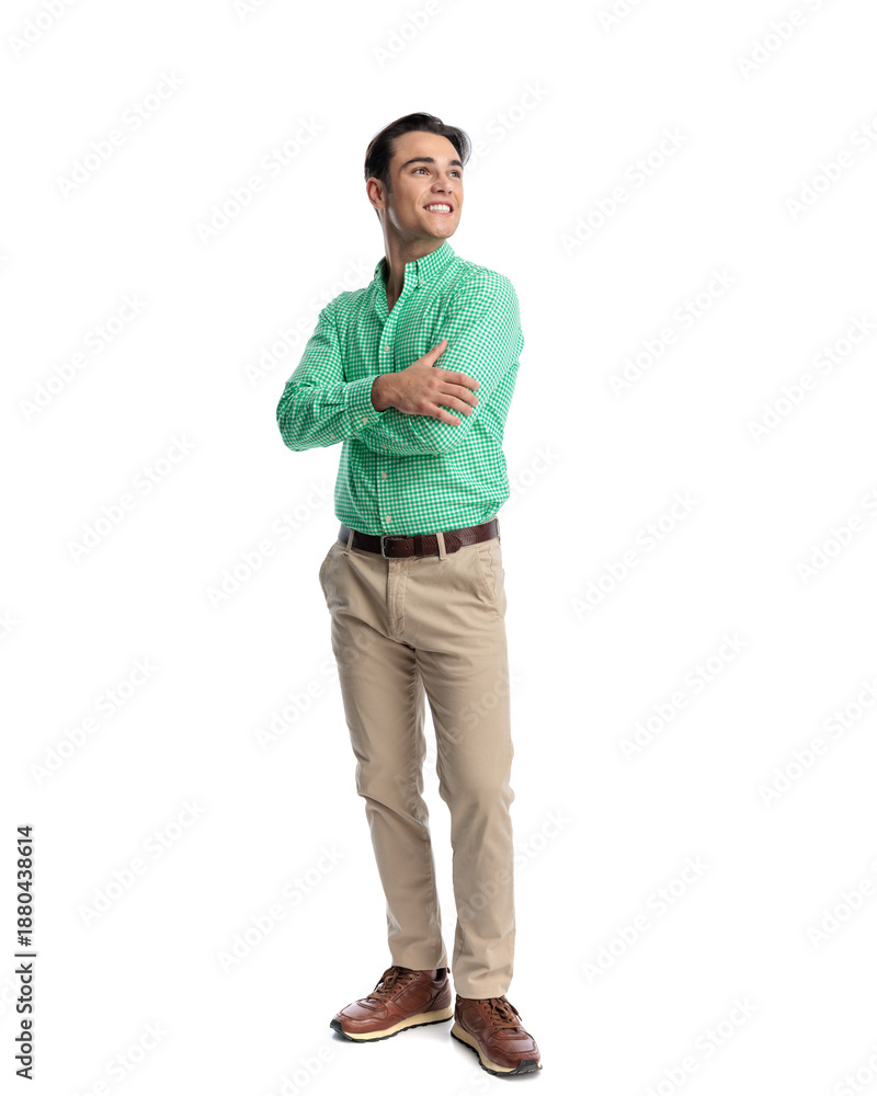 Fototapeta premium Cheerful young man standing with crossed arms looking away