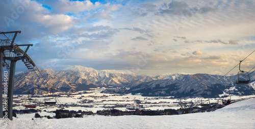 High angle panoramic view of snow covered mountain ranges and Uonuma Basin at sunset from a ski resort (Minamiuonuma, Niigata, Japan)