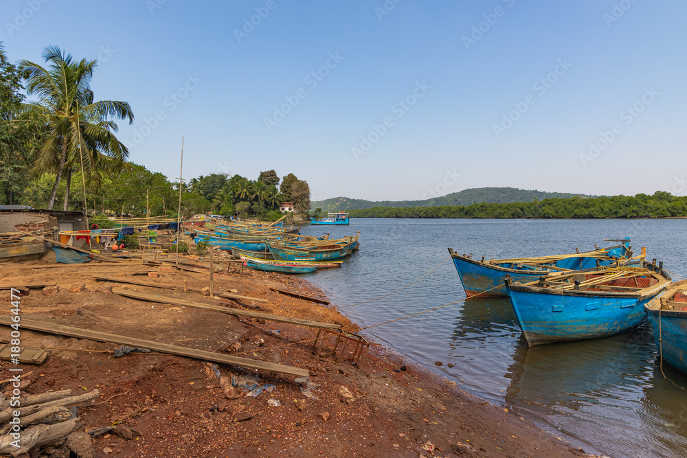 Obraz premium River with lush green river bank and sand mining boats at Goa India