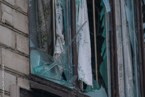 Foto A close-up of a broken window in a residential building, with sharp shards of glass and a curtain