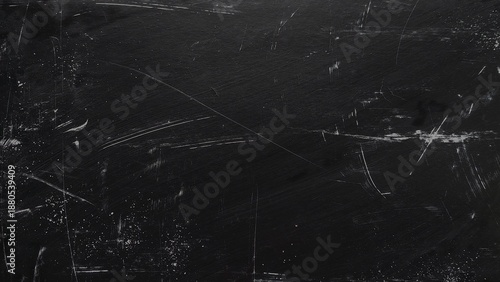 Dark black grunge abstract background with heavy scratches and dust. Dirty black dust texture with noise and distressed overlay. White scratches and dust particles on rough black background.