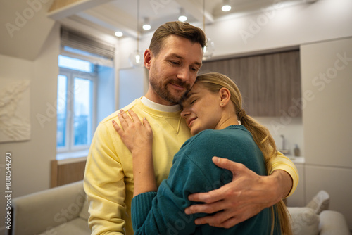 Fotografie Relaxed happy family couple man and woman embracing each other with love, male partner showing genuine protective feelings for girlfriend, tenderly holding female in embrace, shows trust and harmony
