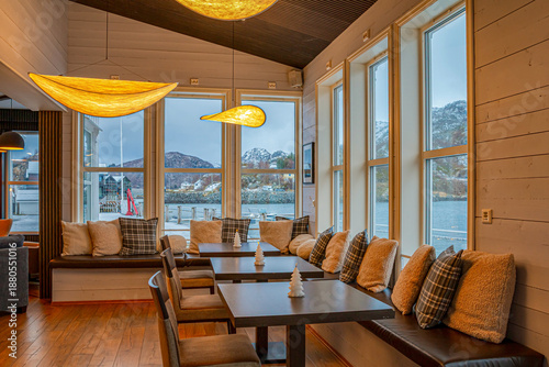 Cozy hotel in Hamn, Norway, during winter, offering warm interiors and stunning views of fjords and snow-covered mountains right outside the windows