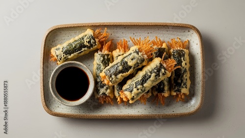 Traditional Korean street food Gimmari, deep-fried seaweed rolls stuffed with glass noodles. Served on a ceramic plate with a side of dipping soy sauce.