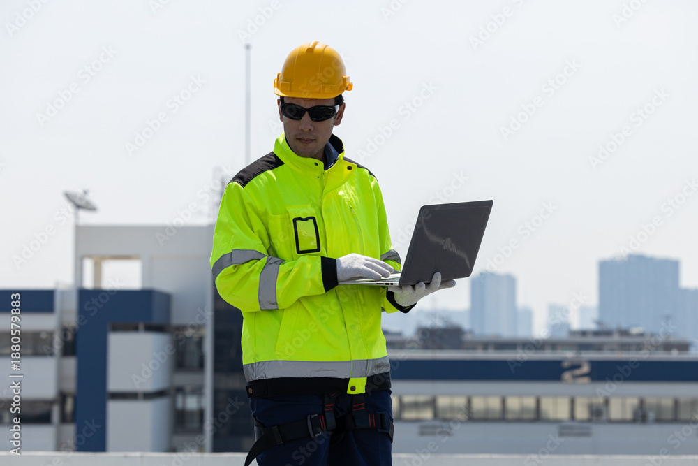 Obraz premium Engineer inspecting solar panels using laptop on rooftop