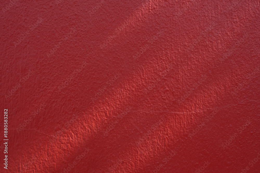 Fototapeta premium Red background painted wall texture with natural light and shadow,showing rough surface detail.Ideal for backgrounds, design material,architectural elements,or construction and interior design project
