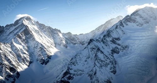 Snowy Mountain Peaks with Clouds and Blue Sky.