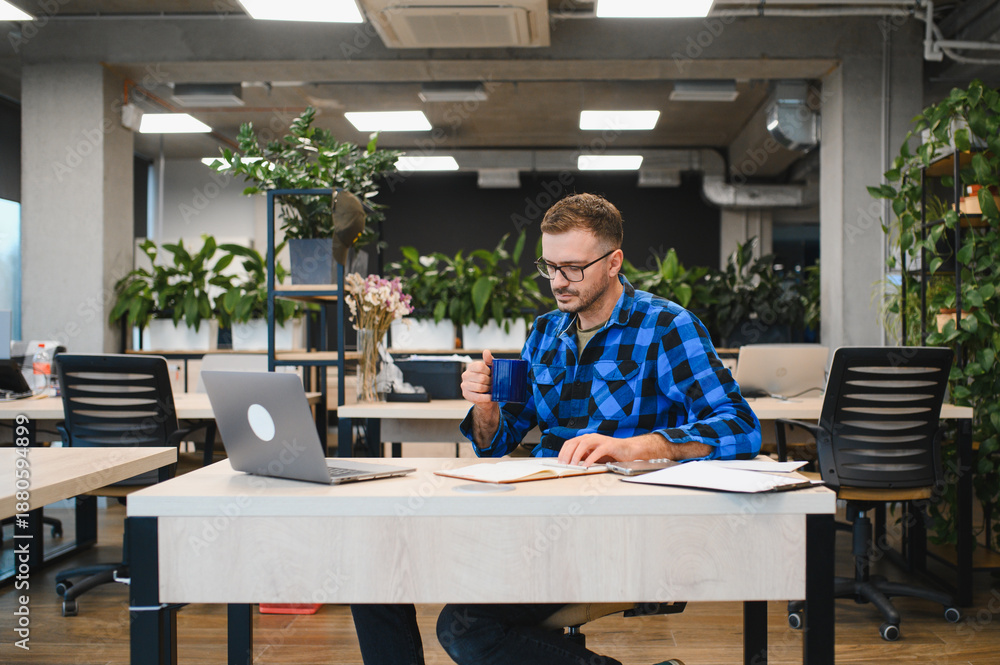 Obraz premium Man working on laptop in modern coworking office