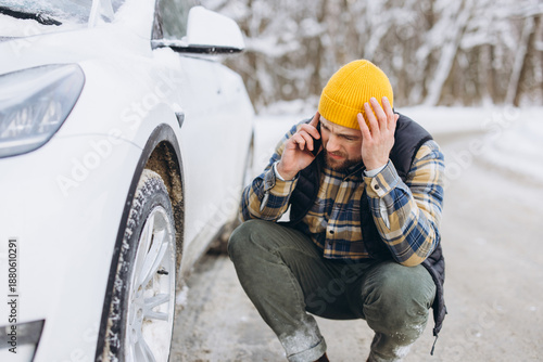Billede på lærred Man experiencing car breakdown in winter, calling for roadside assistance during