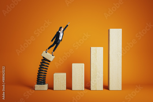 Фотография Businesswoman launching from springboard on wooden bar chart symbolizing career growth and success on vibrant orange background