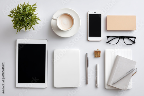 A white tablet sits on a table next to a cup of coffee and a cell phone