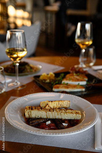 Fotografie Elegantly plated restaurant dinner with gourmet dishes and a glass of wine, fine dining experience, sophisticated and cozy evening meal