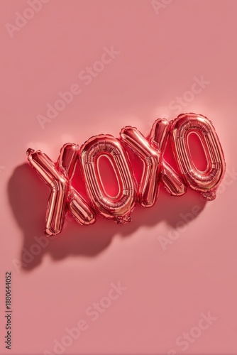 Red foil XOXO balloons on pink background for romantic celebration and party decor