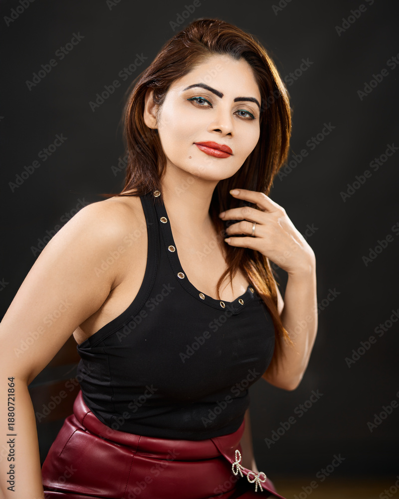 Fototapeta premium Elegant studio portrait of a confident woman with stylish makeup and modern fashion, photographed against a dark background with copy space.