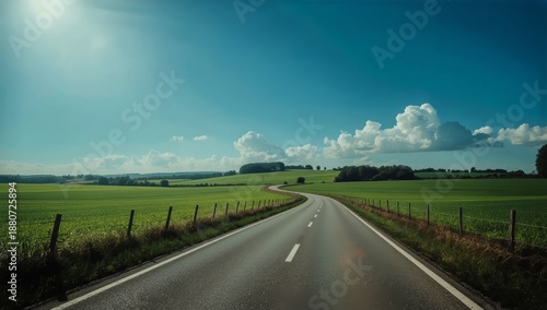 Long Road Winding Through Green Fields Under a Blue Sky With Clouds