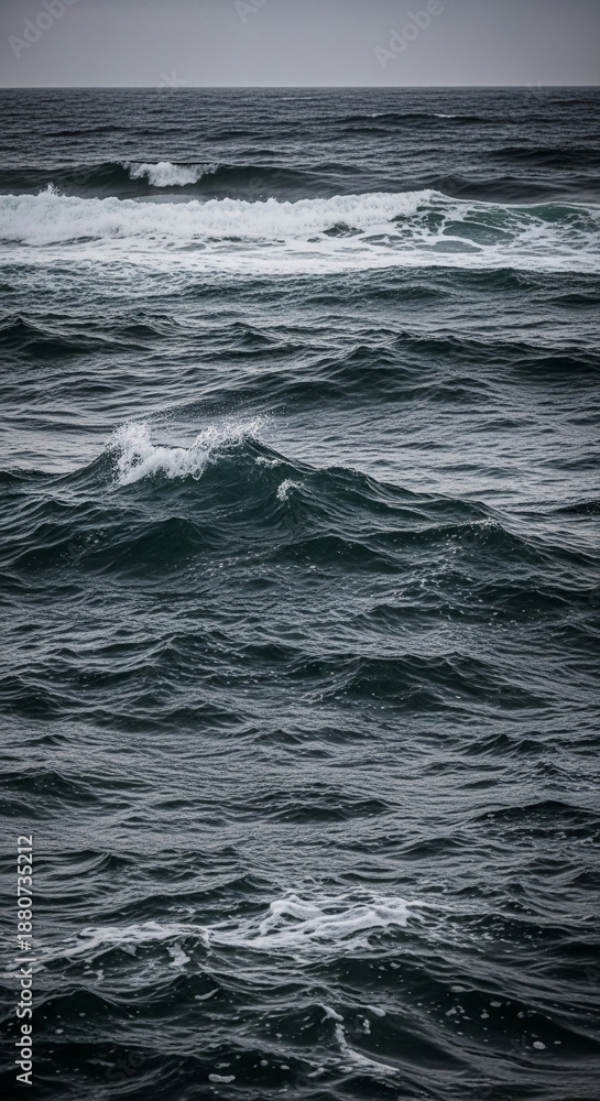 Fototapeta premium Dark ocean water with small waves and foam, creating an undulating surface, representing nature's power and movement, a calming yet dynamic scene