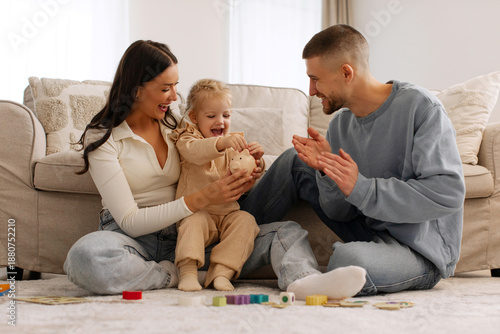 Fotografie Family of three with little girl putting coins in piggy bank, parents and their