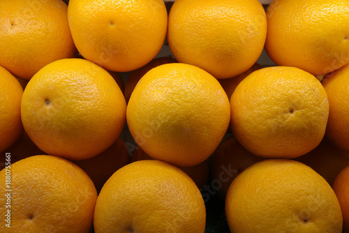 A close-up, meticulously arranged shot captures a grid of vibrant, sun-kissed oranges. The perfectly aligned citrus fruits exhibit a smooth texture, bathing in soft, natural light, emphasizi