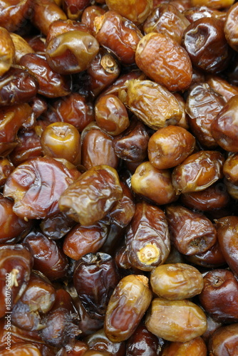 Close-up macro photography of a large pile of Medjool dates showcasing varied textures, hues, and forms, capturing a traditional Middle Eastern food item in a natural, organic arrangement.