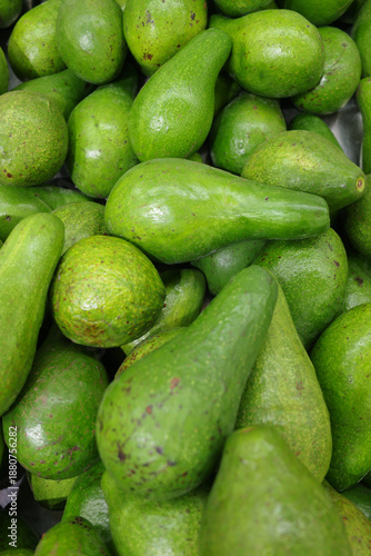 A vibrant, close-up photograph showcasing a pile of fresh, ripe avocados, capturing the natural textures and inviting green hues found within a grocery store setting, perfect for culinary an