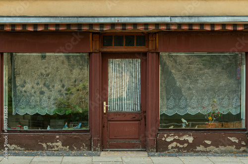 Old closed storefront with weathered facade and large display windows
