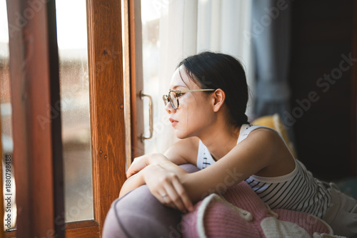 Obraz na plátně Lonely woman looking out window in living room apartment sadness mood unhappy wa