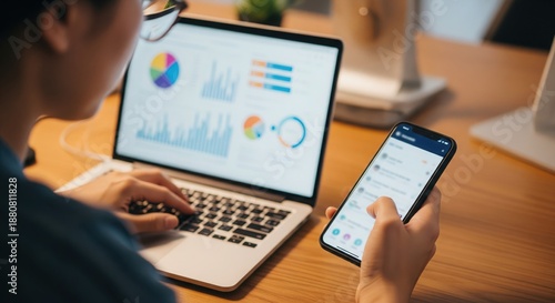 Data Analysis: A close-up shot of a person intently reviewing data on both a laptop and smartphone. The scene highlights the intersection of technology and information.